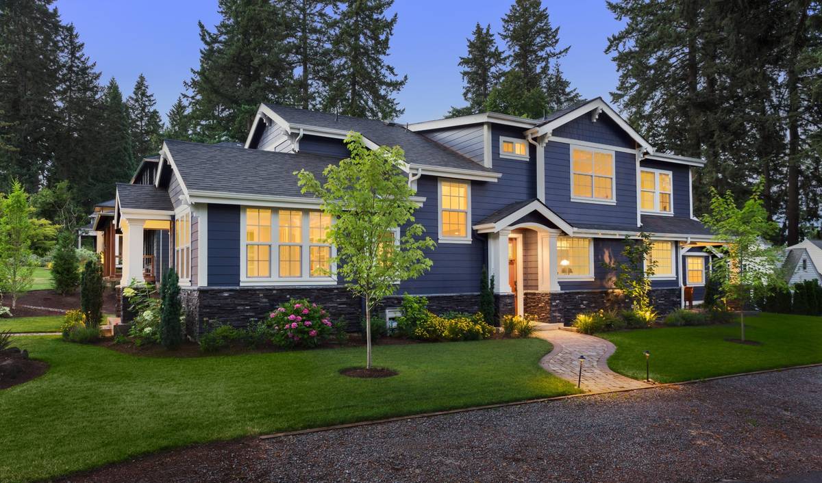 Two-story house at dusk with lit windows, porch lights and low path lights along the front walk