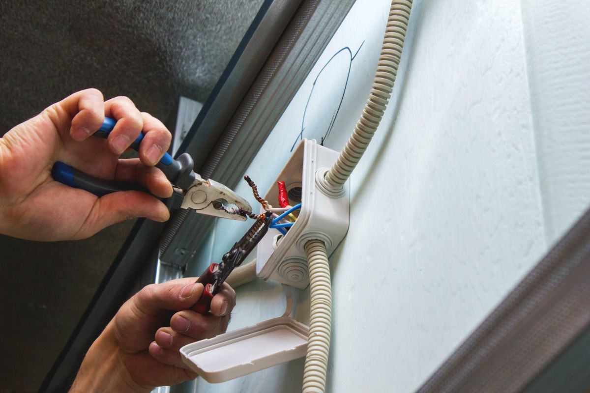Electrician splicing conductors in a surface-mounted junction box fed by flexible conduit