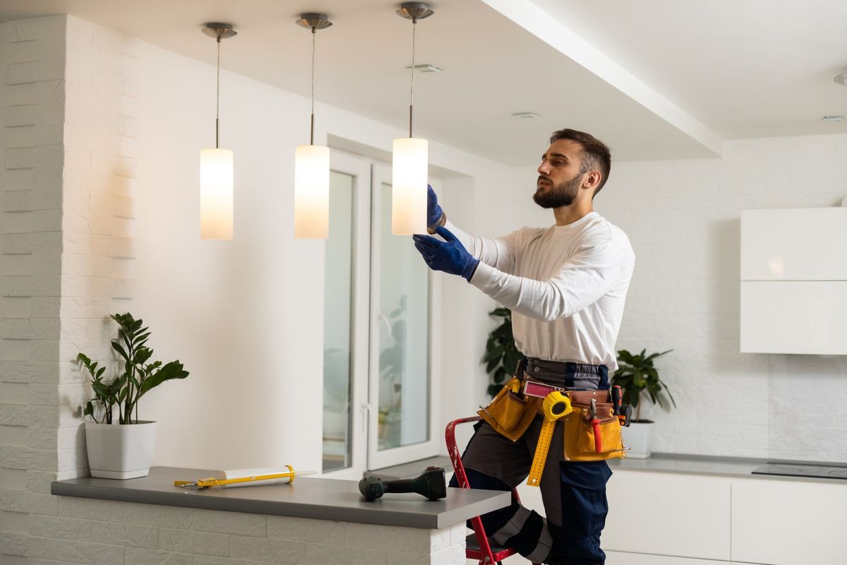 Electrician installing pendant light fixtures over a kitchen counter